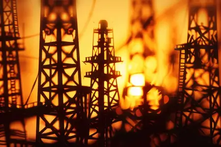 Драматичный силуэт нефтяных буровых установок на фоне красочного заката, иллюстрирующий энергетический сектор