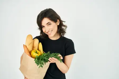 Весёлая брюнетка с пакетом продуктов здорового питания из супермаркета K-supermarket