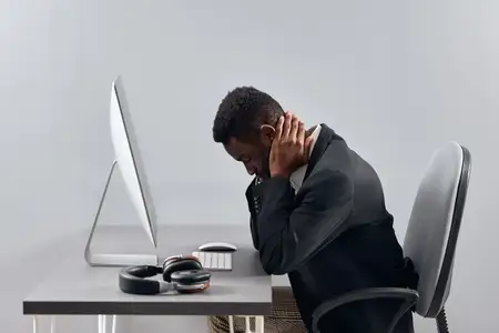 Афроамериканец в наушниках работает за ноутбуком, занимаясь переводом, обучением или видеоконференцией