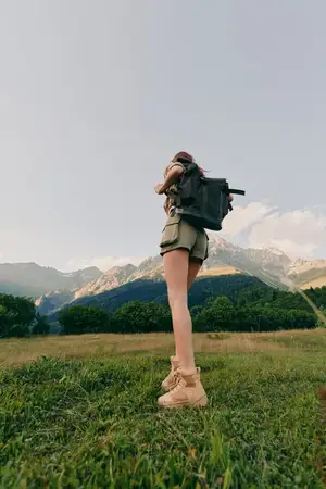 Активная женщина в походе на природе с рюкзаком и ботинками
