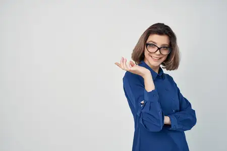 Элегантная женщина в очках и голубой рубашке в студии