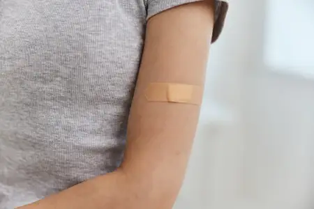 Лейкопластырь на плече женской руки, иммунизация, вакцинация, здоровье, безопасность
