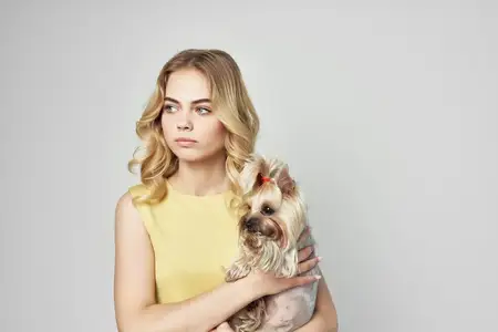 Красивая женщина и домашний питомец позируют в модном стиле на светлом фоне в студии