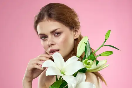 Портрет женщины с белыми цветами, красивое лицо, розовый фон, обнаженные плечи