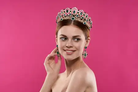 Привлекательная женщина с обнаженными плечами, занимающаяся косметикой, модой и весельем в студии