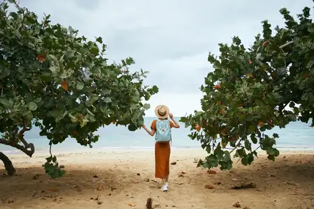 Женщина-туристка с рюкзаком отдыхает у моря на летнем острове