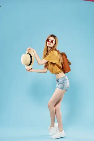 Весёлая симпатичная женщина в шляпе и солнцезащитных очках, с рюкзаком, излучающая эмоции