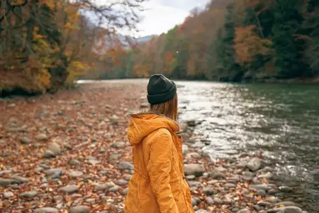 Женщина идет вдоль реки в осеннем лесу, природа, горы