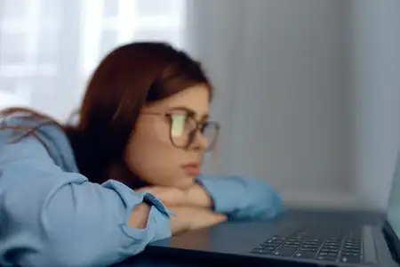 Женщина перед ноутбуком испытывает усталость и нервное напряжение от работы
