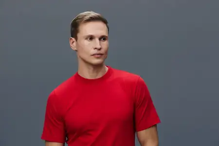 Портрет уверенного молодого человека с короткими волосами, одетого в красную футболку, смотрящего в сторону