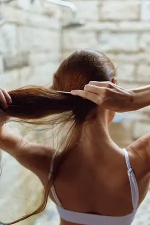 Молодая женщина ухаживает за своими длинными каштановыми волосами в уютной ванной комнате