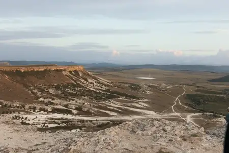 Вид на горную вершину, долину и дорогу в туристическом направлении: мужчина стоит и любуется живописной красотой