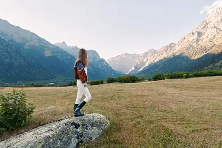 Женщина-туристка исследует альпийскую долину с рюкзаком