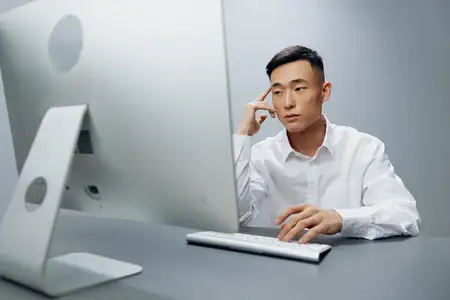 Мужчина в белой рубашке работает за компьютером в офисе на изолированном фоне
