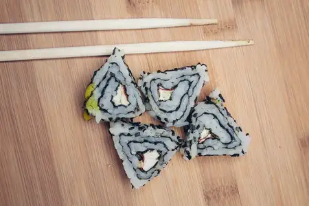 Роллы суши с палочками на деревянной доске, японская кухня