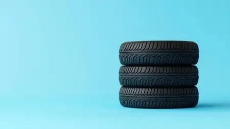 На этом изображении три черных автомобильных покрышки сложены стопкой на фоне ярко-голубого фона, что подчеркивает их качество и дизайн