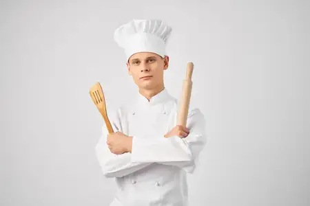 Мужчина в поварской форме готовит на кухне ресторана
