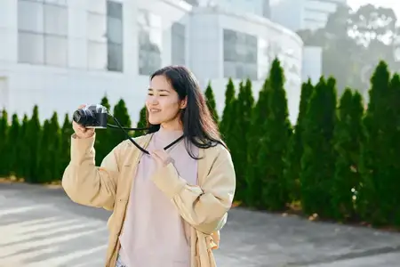Женщина-фотограф с камерой в руках снимает уличные сцены на территории современного кампуса