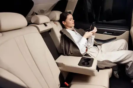 Женщина на заднем сиденье автомобиля держит смартфон, сосредоточенно глядя на экран