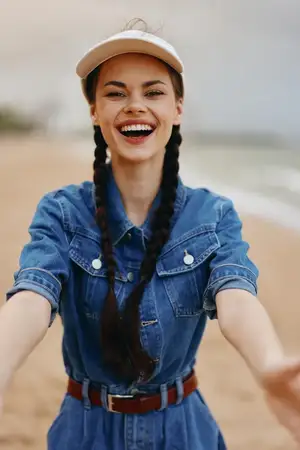 Радостная мода: молодые улыбающиеся женщины с красивыми каштановыми волосами счастливо позируют на открытом воздухе на солнечном пляже на фоне осеннего моря