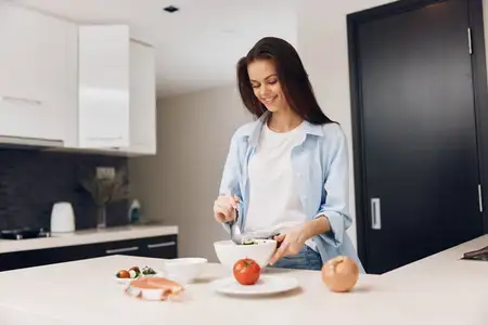 Женщина готовит полезное блюдо на кухне, используя свежие овощи, рядом стоит тарелка с аппетитной едой