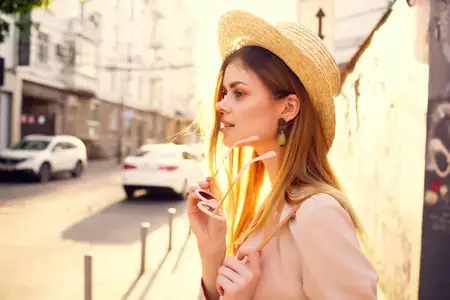 На улице стоит красивая женщина в шляпе и очках
