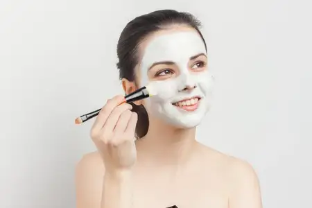 Эмоциональная брюнетка с маской для лица, обнаженные плечи, уход за кожей