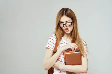 Студентка с блокнотом и в очках на светлом фоне, кадрированный вид