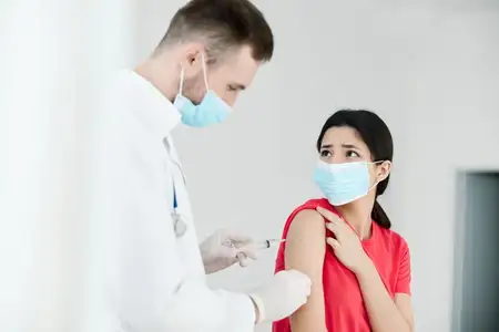 Врач-мужчина в белом халате делает пациенту инъекцию в плечо