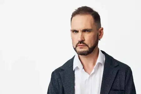 Субъект излучает серьезные, задумчивые эмоции, глядя вперед, что предполагает стратегическое планирование и эффективное принятие решений на ярком изолированном цветном фоне