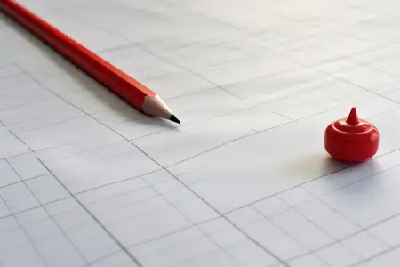 На чистом листе бумаги в клетку лежат ручка и карандаш на белом фоне