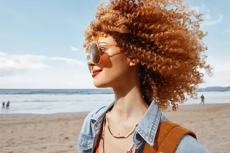 Улыбающаяся женщина с рюкзаком наслаждается счастливым пляжным отдыхом
