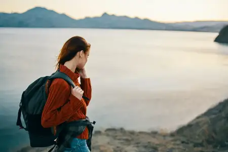 Красивая женщина, которая смотрит назад, туризм, путешествия, горный пейзаж, закат, модель