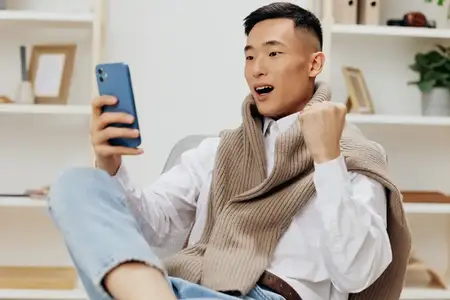 Подросток общается по телефону, сидя на стуле в интерьере