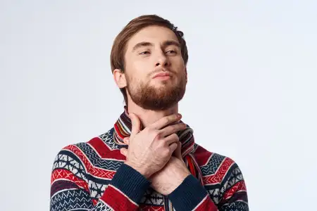 Мужчина, которому холодно, испытывает боль в горле, симптомы гриппа и проблемы со здоровьем на изолированном фоне