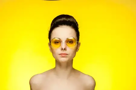 Привлекательная брюнетка в желтых очках с обнаженными плечами, чистая кожа, гламур