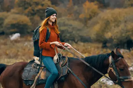 Женщина-туристка верхом на лошади в горах