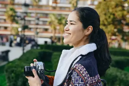 Женщина с фотоаппаратом в руках, занимающаяся фотографией в парке