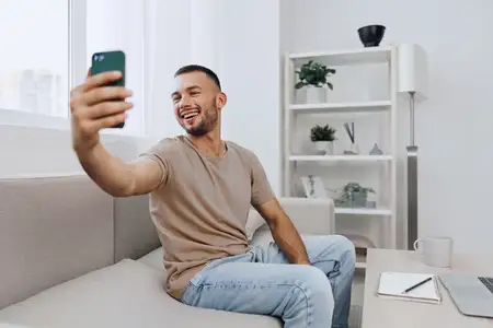 Счастливый мужчина участвует в откровенном видео-звонке из своей уютной гостиной