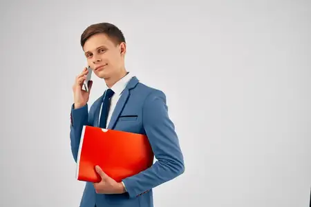 Мужчина в костюме держит в руках красную папку и телефон для общения