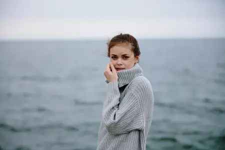 Женщина в свитерах стоит у облачного моря, восхищаясь природой