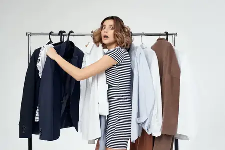 Симпатичная женщина-шопоголик выбирает одежду в магазине на изолированном фоне