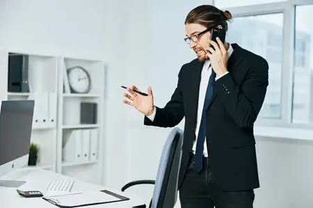 Офисный работник с документами в руках общается по телефону