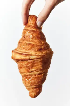 Круассан, который держит человек, на белом фоне
