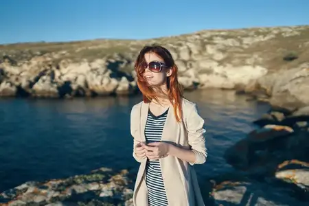 Женщина-туристка в футболке и очках на природе в горах