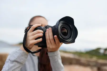 Молодая женщина в повседневной одежде занимается фотографией на открытом воздухе