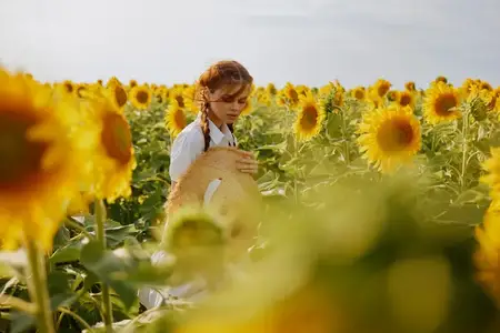 Женщина с косичками в поле подсолнухов, сельская местность