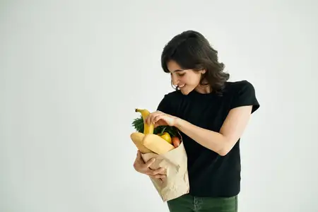 Женщина с сумкой для покупок, домохозяйка, выбирающая овощи в супермаркете