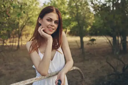 Женщина в белом платье прогуливается по полю среди деревьев на природе