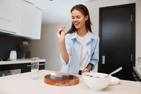 Счастливая молодая женщина готовит вкусную еду на уютной домашней кухне